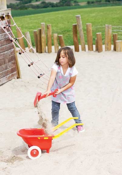 Schubkarre Kunststoff mit Kind im Sand hinten