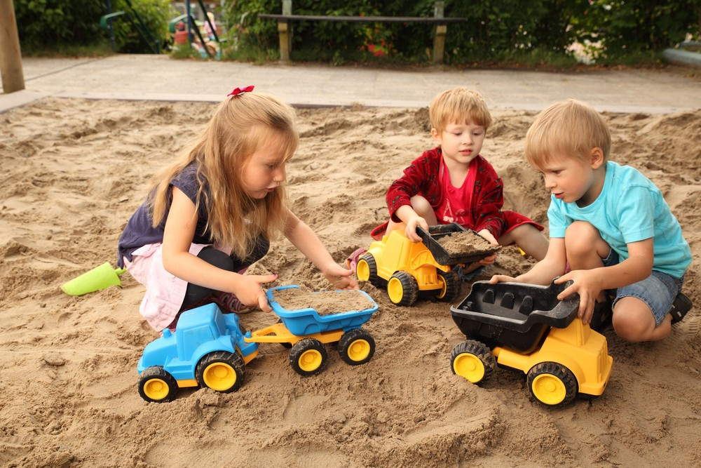 Kipplaster mit Kindern im Sand links